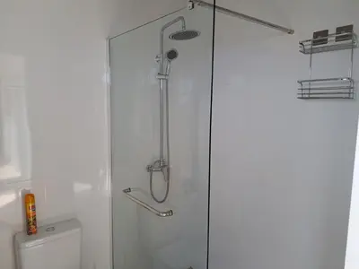 a shower with a glass door next to a toilet at Success House in Calheta