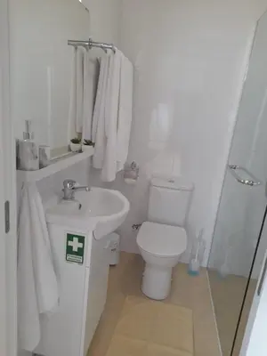 a white bathroom with a toilet and a sink at Success House in Calheta