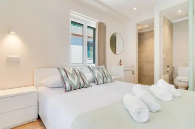 a white bedroom with two beds and a bathroom at Q Studios by Atlantic Holiday in Funchal