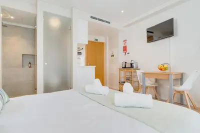 a white bedroom with a large bed and a kitchen at Q Studios by Atlantic Holiday in Funchal