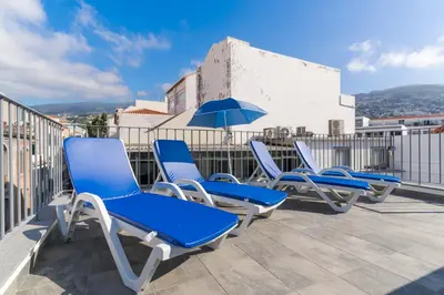 a group of blue chairs and an umbrella on a roof at Q Studios by Atlantic Holiday in Funchal