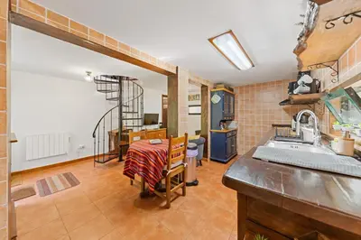 a kitchen and dining room with a table and a sink at Mountain View Cottage in Seixal