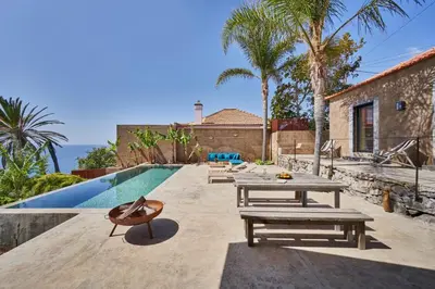 a backyard with a pool and picnic tables next to a house at Pirate House Sea front Private Pool Garden Funchal in Funchal