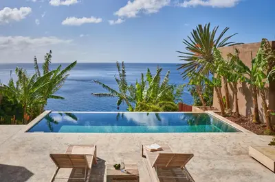 a pool with chairs and the ocean in the background at Pirate House Sea front Private Pool Garden Funchal in Funchal