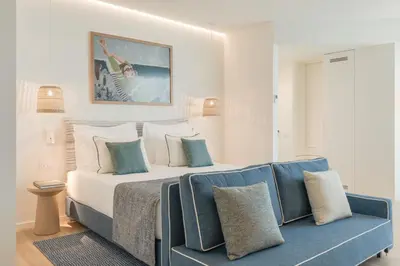 a bedroom with a bed and a blue couch at The Editory Ocean Way Funchal in Funchal