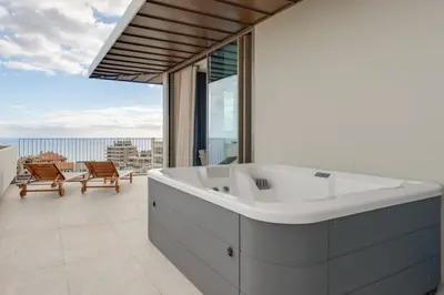 a bath tub in a bathroom with a view of the ocean at The Editory Ocean Way Funchal in Funchal