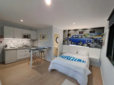 a bedroom with a bed and a kitchen with a car on the wall at Classic Car House in Santa Cruz