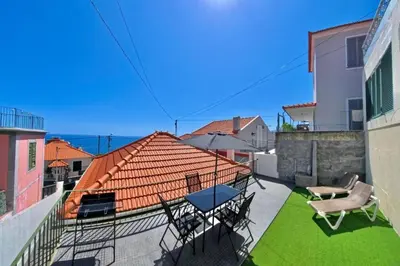 a balcony with chairs and tables and a roof at Madeira Breeze in Funchal