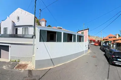 a white building with green shutters on a street at Madeira Breeze in Funchal