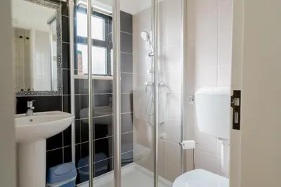 a white bathroom with a shower and a sink at 5 bedroom Beach house in Luz, Lagos in Luz