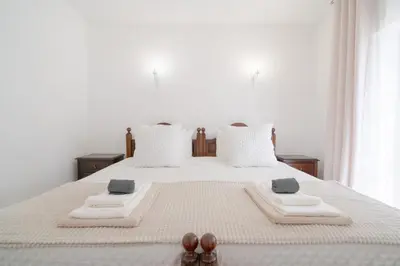 a white bed with two towels and two slippers on it at 5 bedroom Beach house in Luz, Lagos in Luz