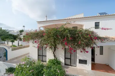 a white house with a tree with pink flowers at 5 bedroom Beach house in Luz, Lagos in Luz