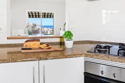 a kitchen counter with a cutting board with a loaf of bread at Vila Agora Luz in Luz