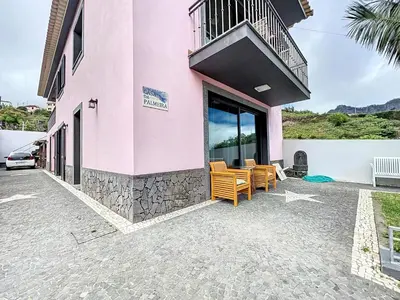 a pink building with chairs and a balcony at Casa da Palmeira in Machico