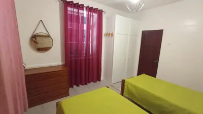 a bedroom with two beds and a dresser and curtains at Bus Stop House 82 in Funchal