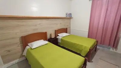 two beds with green sheets in a room at Bus Stop House 82 in Funchal