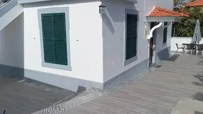 a white house with green shutters and a patio at Bus Stop House 82 in Funchal