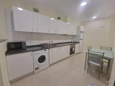 a kitchen with white cabinets and a table and a washing machine at Atlantic Garden Santa Luzia 44 in Funchal
