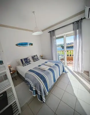 a bedroom with a bed and a large window at Apartamento Sagres Sunset in Sagres