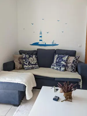 a blue couch in a living room with a lighthouse on the wall at Apartamento Sagres Sunset in Sagres