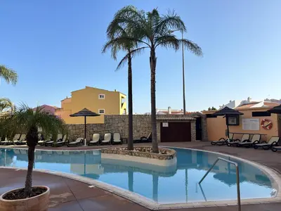 a swimming pool with palm trees in a resort at Seaview apartment Estrela da Luz Praia da Luz in Luz