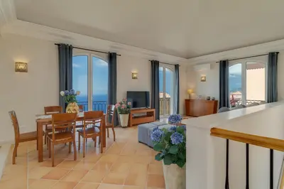 a living room with a table and chairs and a living room with windows at Villa Eve Palheiro Village by Holiday Rental Madeira in Funchal