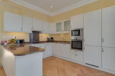 a large white kitchen with white cabinets and appliances at Villa Eve Palheiro Village by Holiday Rental Madeira in Funchal