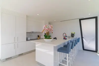 a kitchen with white cabinets and a counter with blue chairs at Luxury Diamond House by Holiday Rental Madeira in Funchal
