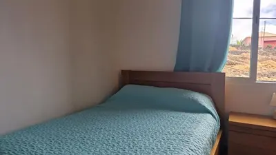 a bedroom with a bed and a window with blue curtains at Jose's cozy little home in Funchal