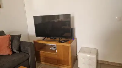 a flat screen tv on a wooden stand in a living room at Jose's cozy little home in Funchal