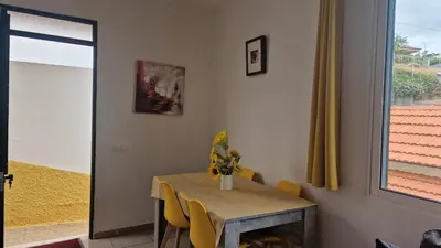 a dining room with a table and yellow chairs at Jose's cozy little home in Funchal