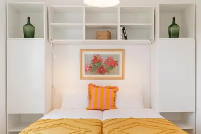 a bedroom with white shelves and a bed with a colorful pillow at Bela de Santiago I by An Island Apart in Funchal