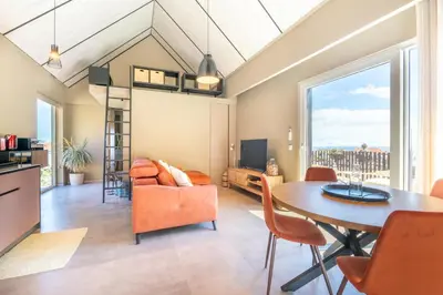 a dining room and living room with a table and chairs at Doca Seca & Casca de Uva in Porto Moniz