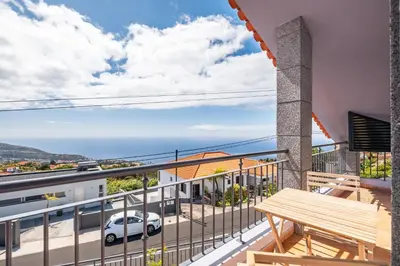 a balcony with a wooden bench and a view of the ocean at Linda Paisagem in Calheta