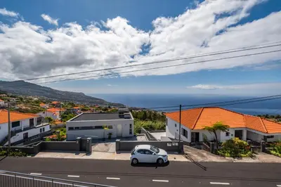 a white car parked on a street with houses at Linda Paisagem in Calheta