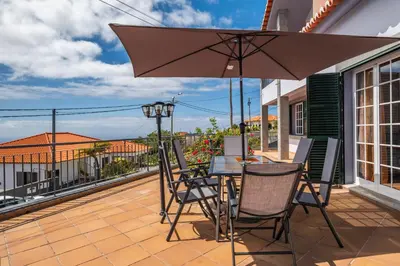 a patio with a table and chairs and an umbrella at Linda Paisagem in Calheta