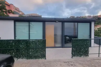 a house with glass windows and green bushes at Villa Castanho II in Calheta