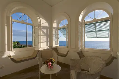 a room with three windows and a table with flowers on it at Casa da Madalena do Mar in Madalena do Mar