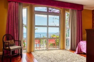 a bedroom with a large window with a view of the ocean at Casa das Bromélias, a Home in Madeira in Funchal