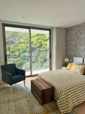 a bedroom with a bed and a chair and a window at Cardais Paradise View in São Vicente