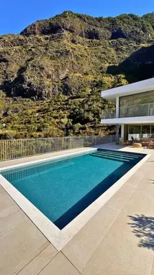 a swimming pool in front of a house with a mountain at Cardais Paradise View in São Vicente