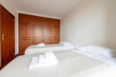 two beds in a bedroom with white sheets and towels at Madeira Sunny Penthouse in Funchal