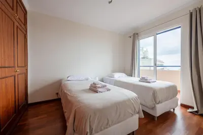 two beds in a room with a large window at Madeira Sunny Penthouse in Funchal