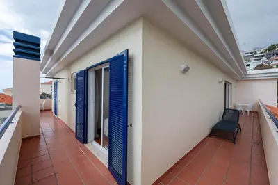 a balcony of a house with blue doors and a chair at Madeira Sunny Penthouse in Funchal