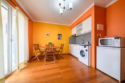 a kitchen with orange walls and a table with chairs at Gabriel Loft by MTH in Ponta do Sol
