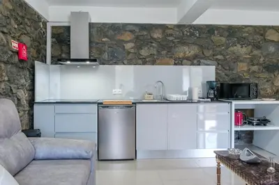 a kitchen with white cabinets and a stone wall at GuestReady - Delight Getaway in Madeira in Machico