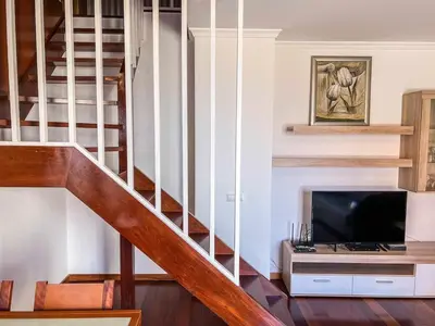 a living room with a staircase and a flat screen tv at Rosalina's Apartment in Caniço