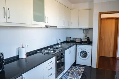 a kitchen with white cabinets and a washer and dryer at Rosalina's Apartment in Caniço