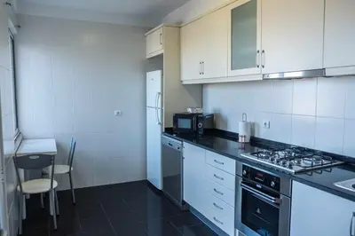 a kitchen with white cabinets and a stove top oven at Rosalina's Apartment in Caniço