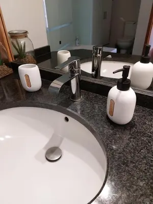a bathroom counter with a sink and two soap dispensers at Rosalina's Apartment in Caniço